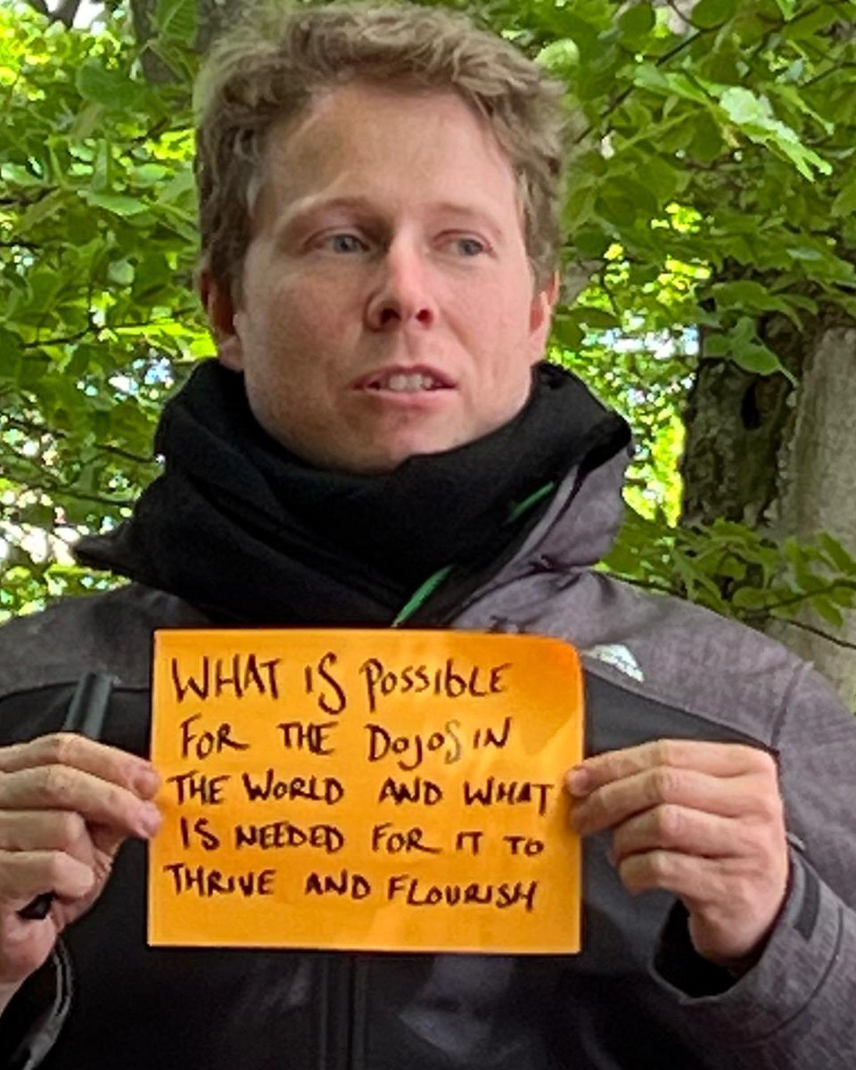 Philip Marken outdoors under trees, holding a handwritten calling question.