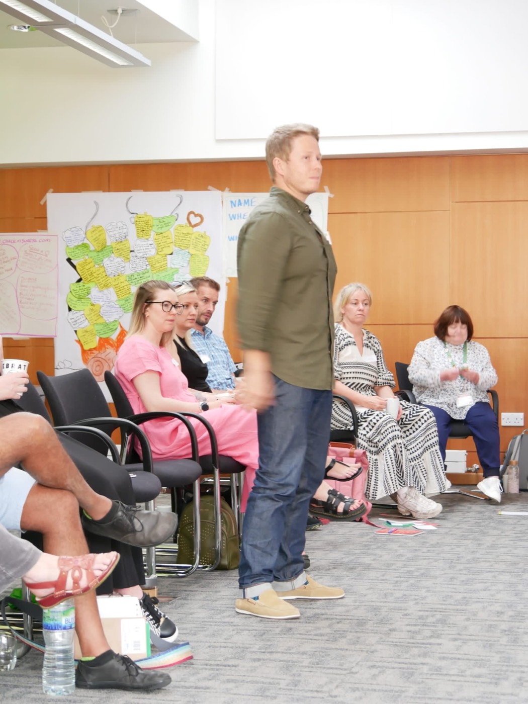 Philip Marken standing in front of a seated room of workshop participants, mid-conversation, harvest charts taped to the wall behind him.